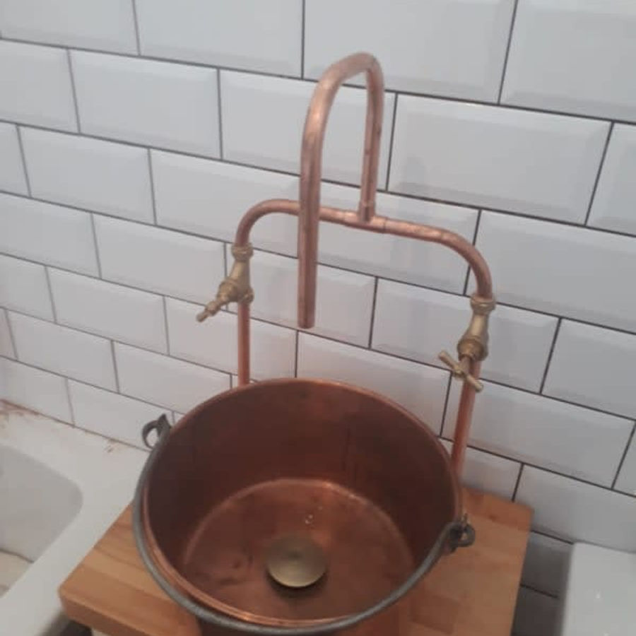 Round copper basin and tiled wall